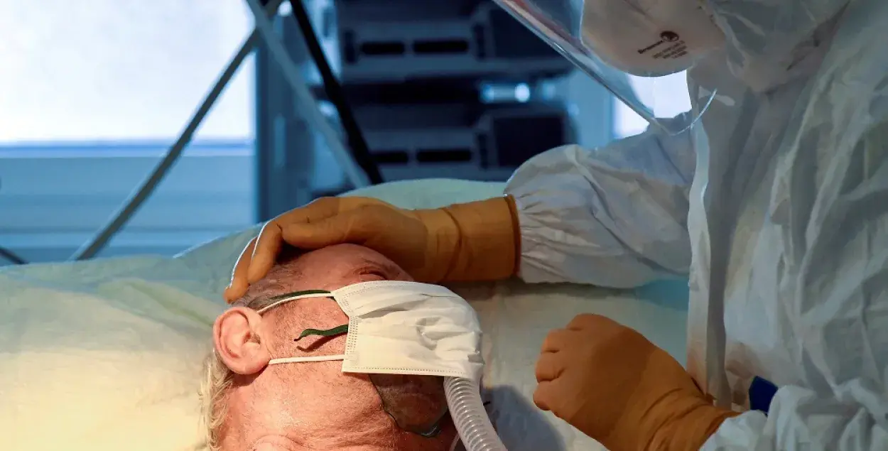 Медицинский работник утешает пациента, больного коронавирусом / Reuters