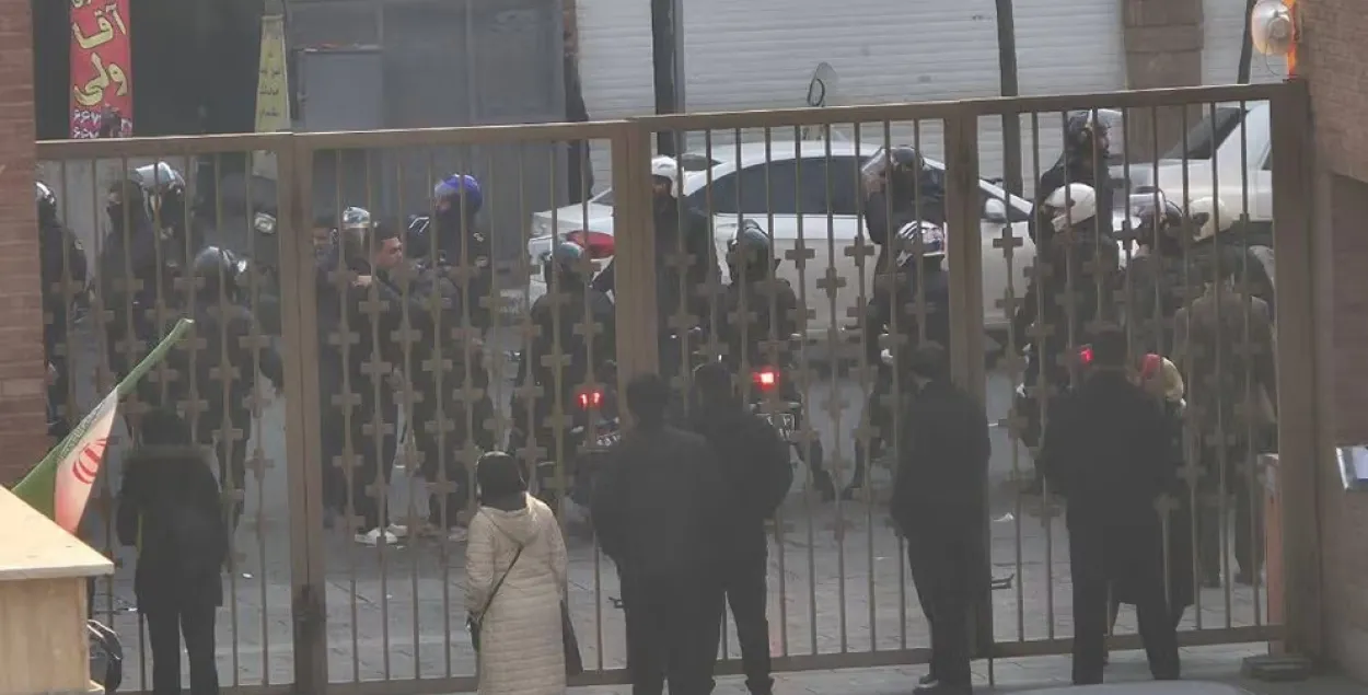 Силовики стоят за воротами больницы в Тегеране, где, по словам очевидцев, некоторые протестующие искали убежище во время столкновений 6 января 2026 года
