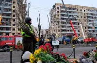 Людзі нясуць кветкі, знічкі і цацкі да разбуранага будынка ў Дняпры / RFE/RL
