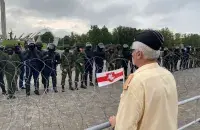 Пратэстовец стаіць насупраць ланцугу вайскоўцаў, трымаючы ў руках бел-чырвона-белы сцяжок 23 жніўня 2020 года / Еўрарадыё