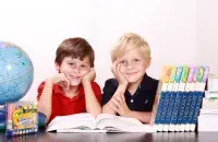 Дети за партой с учебниками и глобусом