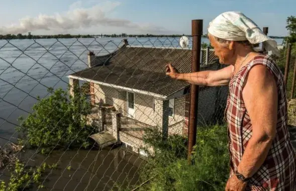 Жительница Новой Каховки на Херсонщине смотрит, как вода затапливает соседние дома / Reuters
