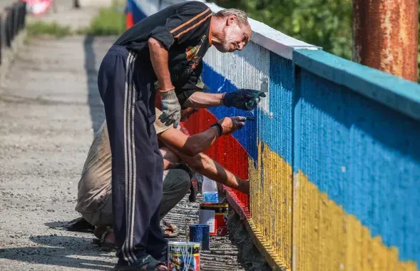 Мужчыны перафарбоўваюць мост ва Украіне / ura.ru
