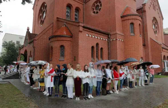 Жанчыны ўтвараюць жывы ланцуг перад касцёлам святых Сымона і Алены ў Мінску, 27 жніўня 2020 года
