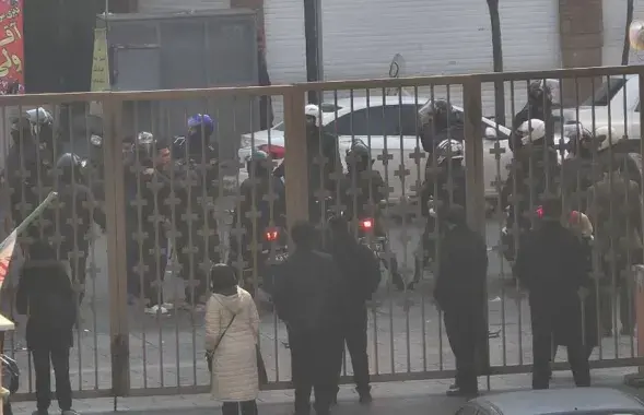 Силовики стоят за воротами больницы в Тегеране, где, по словам очевидцев, некоторые протестующие искали убежище во время столкновений 6 января 2026 года
